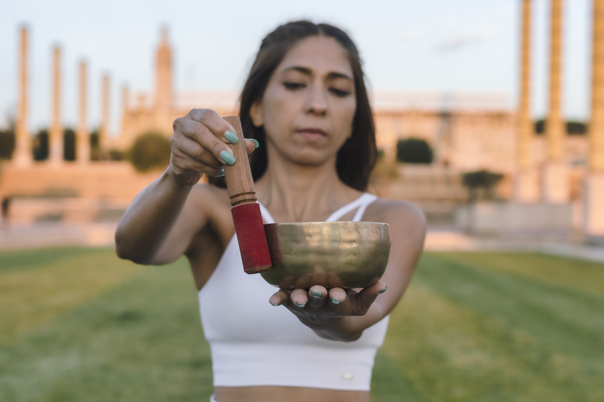 Imagen de una mujer sosteniendo un cuenco tibetano, símbolo de meditación y relajación, evocando la conexión interior y la práctica de sonidos sanadores.